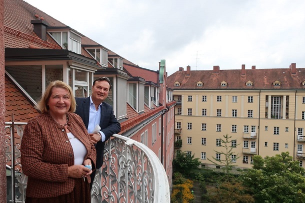 Zwei Menschen auf einem Balkon, lächelnd