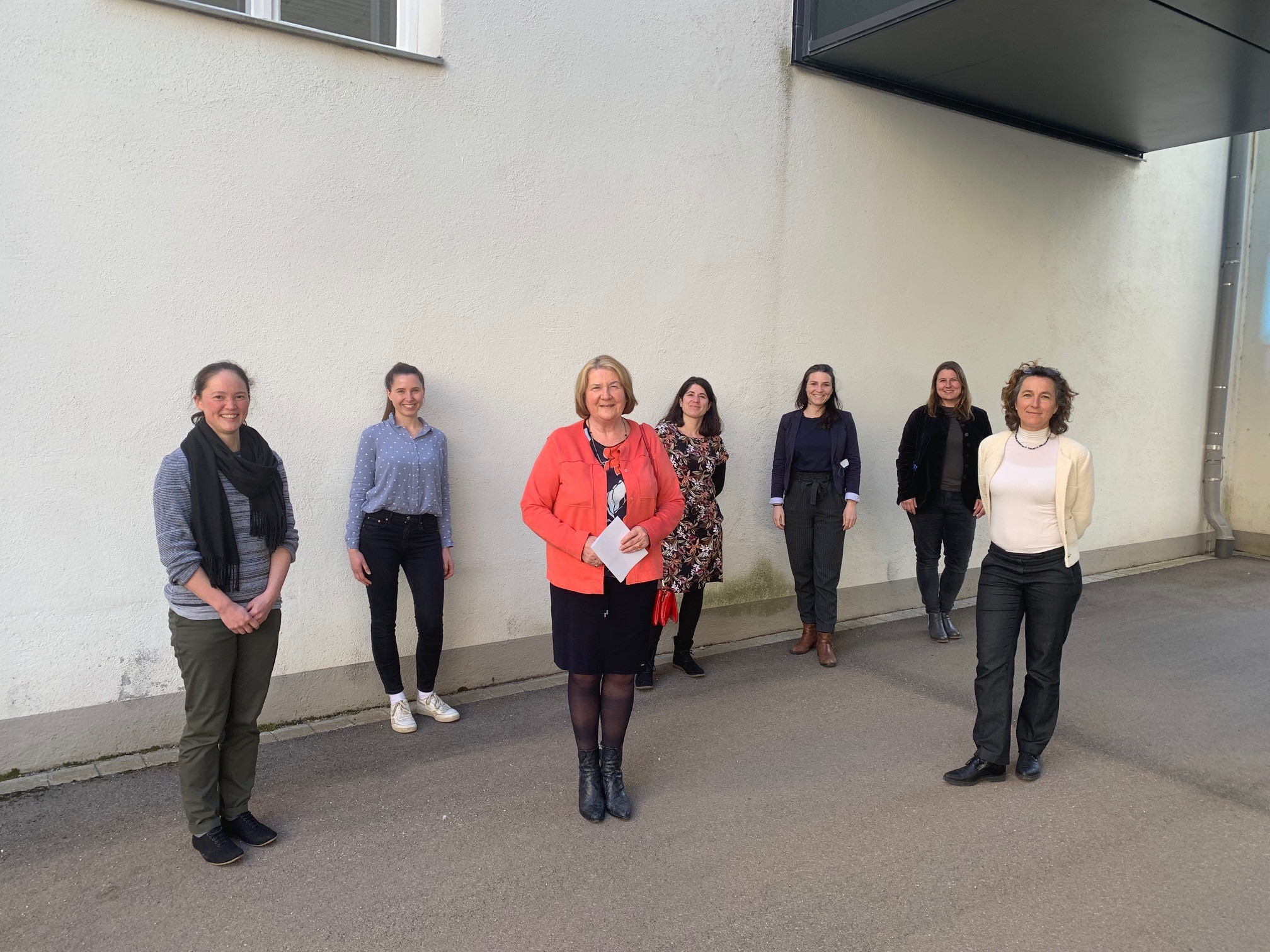 sieben Frauen, draußen, vor einer Wand, nehmen Aufstellung