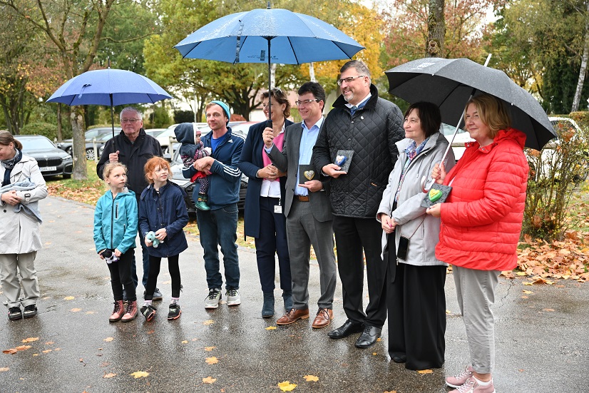 Elf Personen, darunter Kinder, an der frischen Luft, regnerisch, Regenschirme