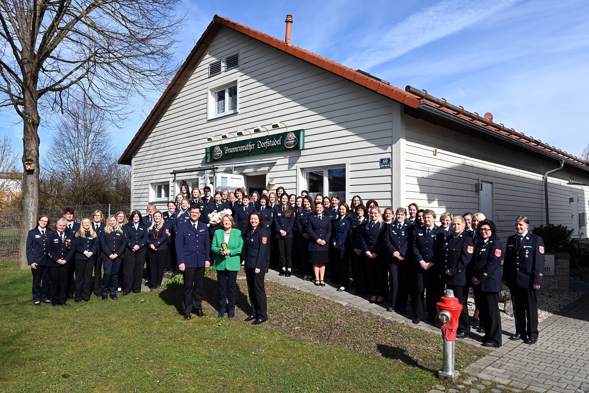 Gruppenfoto mit aktiven Feuerwehrlern vor einem Gasthof bei Sonnenschein