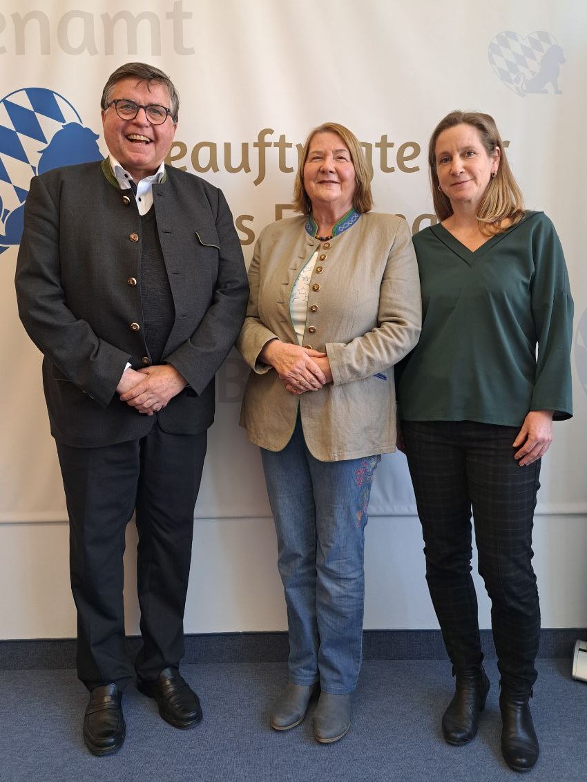 3 Personen vor einer Fotowand lächeln