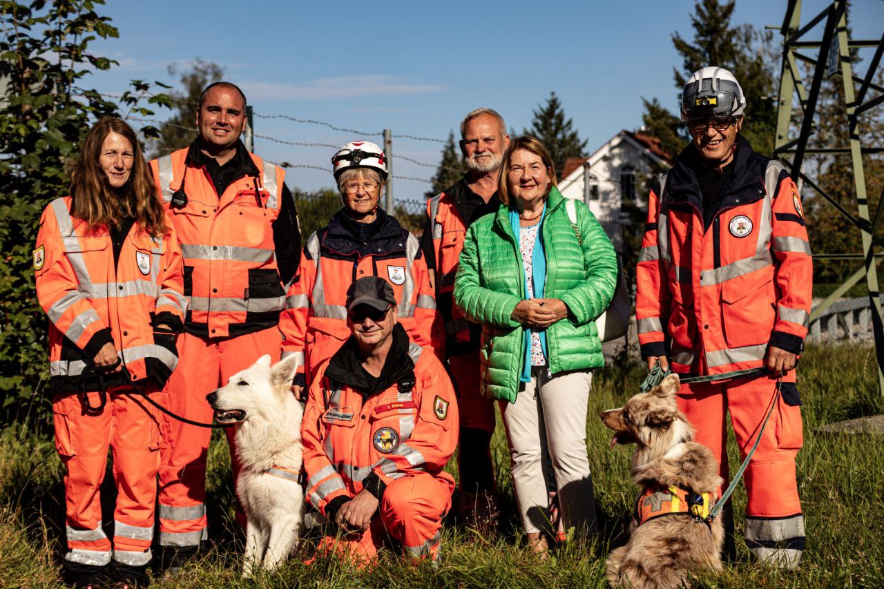 Gruppenfoto mit Helferinnen und Helfern in Uniform, in der Mitte ein Suchhund