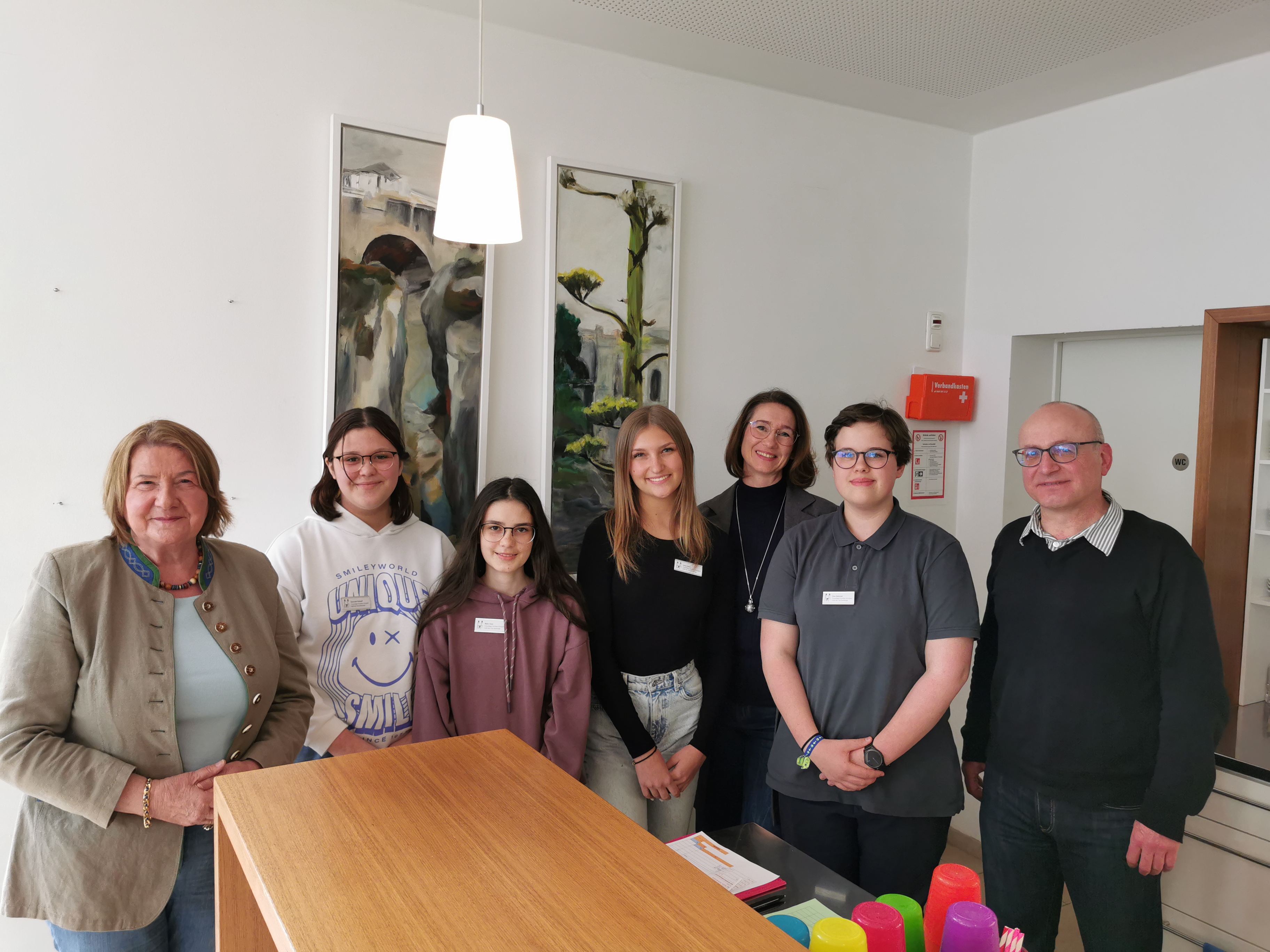 Menschen stehen hinter einem Tisch und lächeln